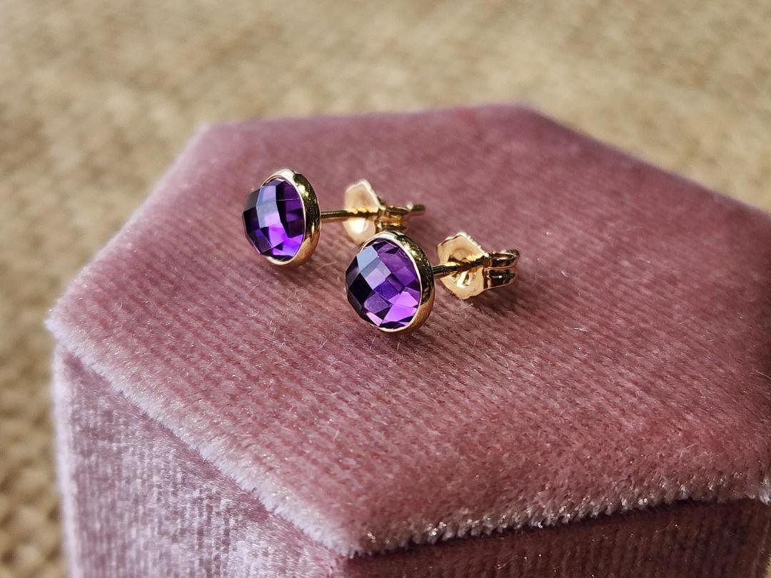 two earrings in yellow gold with a round rose cut amethyst on a pink velvet box