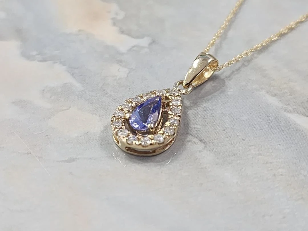 side view Tanzanite and diamond necklace with a grey and tan imitation marble background