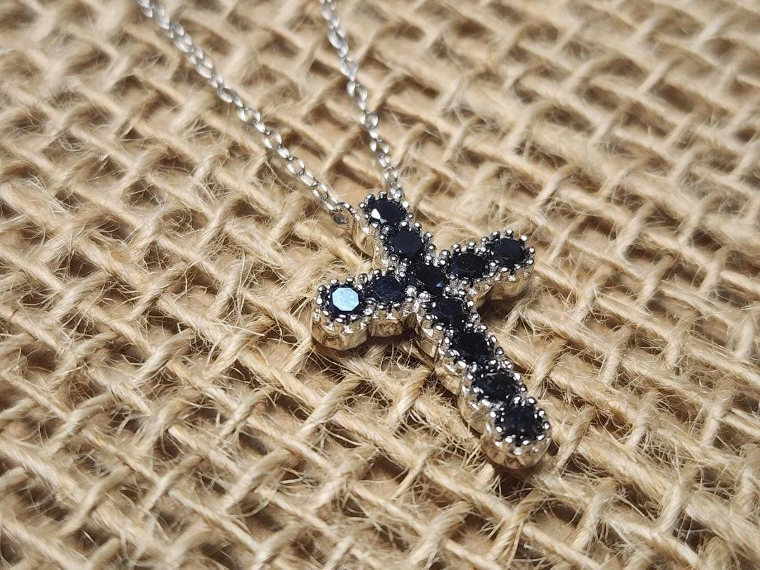 side view Black diamond cross with silver details on a burlap background