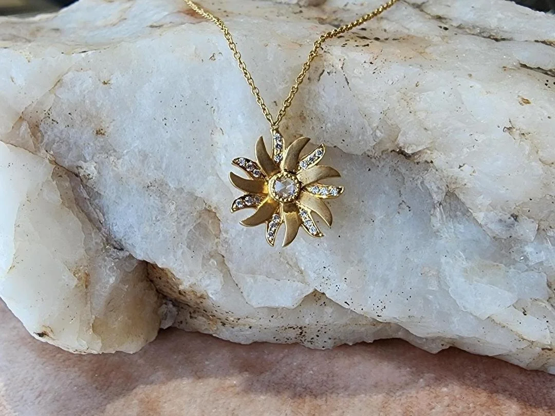 yellow gold diamond flower necklace on white quarts rock and pink velvet