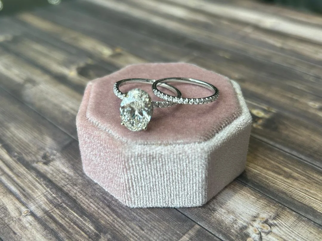 white gold wedding ring set and matching wedding band with diamond accents on pink velvet box and wood in background