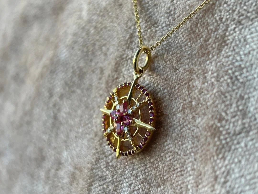 side view ruby and diamond compass necklace with velvet background