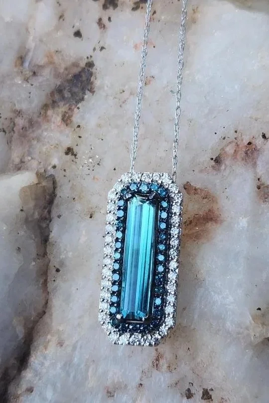bi colored emerald cut tourmaline blue to green with a double halo of diamonds on a rock