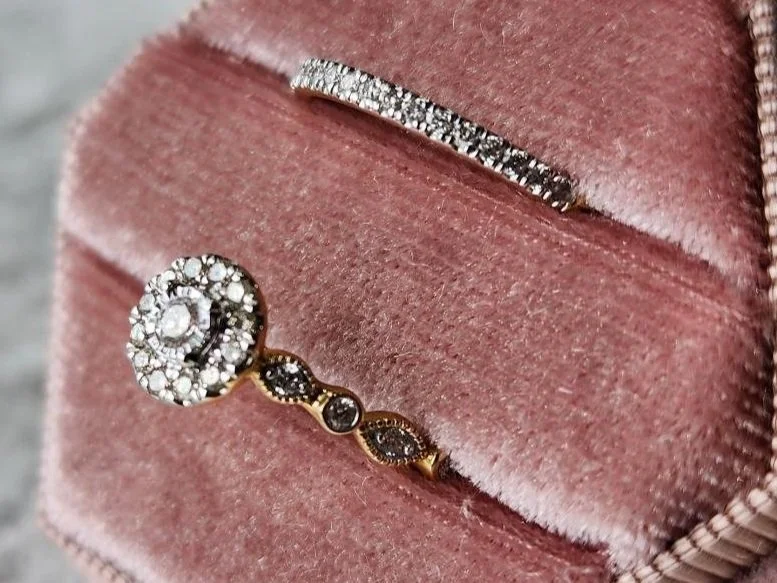 side view One yellow gold wedding ring set with round diamond halo engagement ring and straight diamond wedding band in pink box on grey fabric