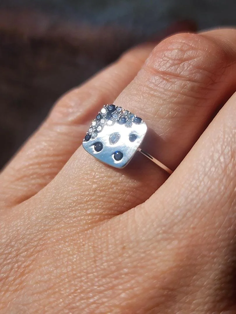 White gold sapphire and diamond ring with square design on women's hand