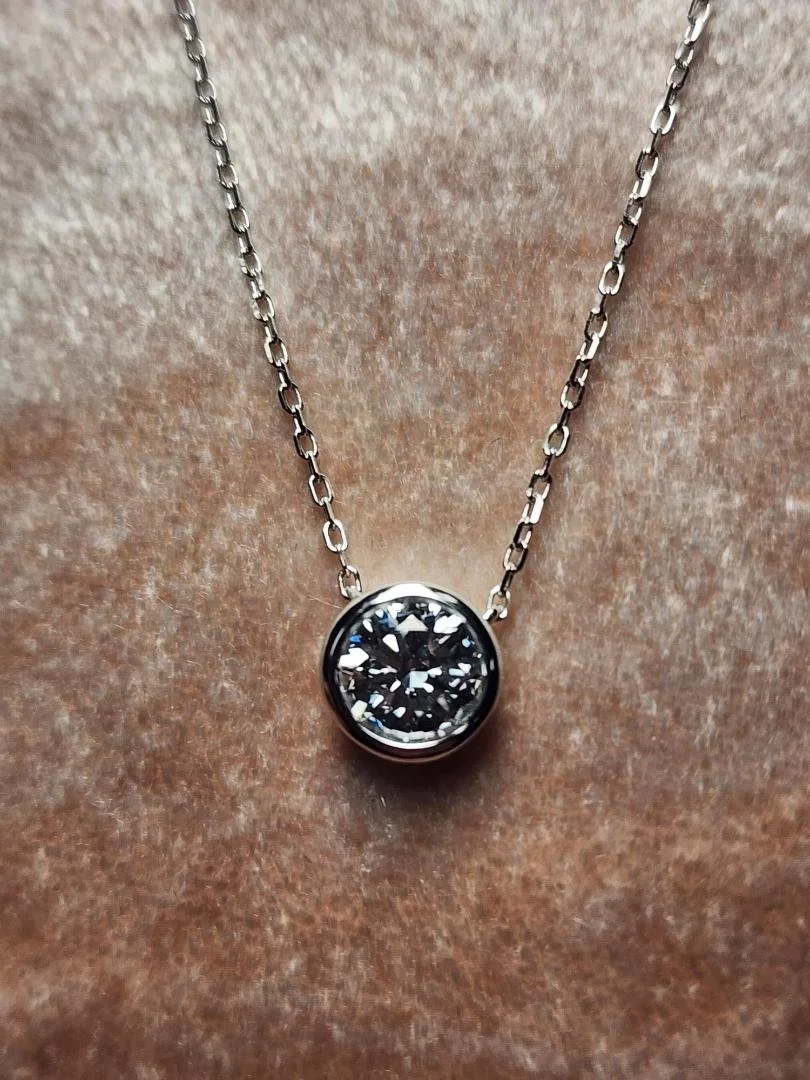 round lab grown diamond necklace on a silver chain on pink velvet