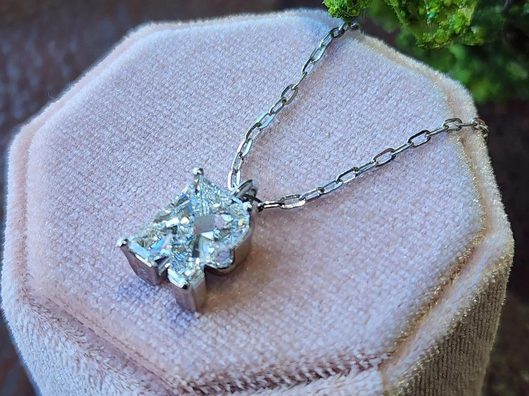 side view of Fancy Cut R lab grown diamond necklace in white gold on a pink box