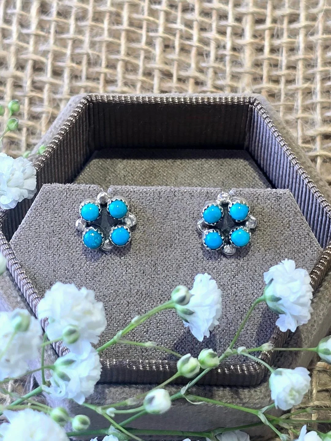 Front view of silver turquoise studs in a brown bracelet with small white flower set on top