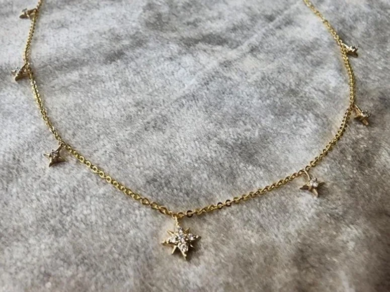 yellow gold diamond star necklace on grey fabric