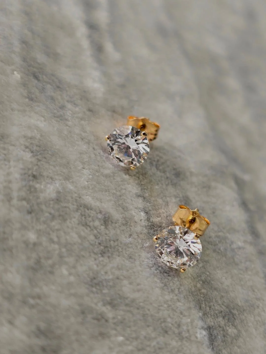 Front angled view of lab grown diamond studs set on a grey velvet background