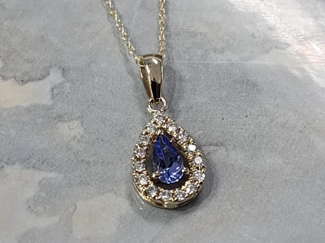 Tanzanite and diamond necklace with a grey and tan imitation marble background
