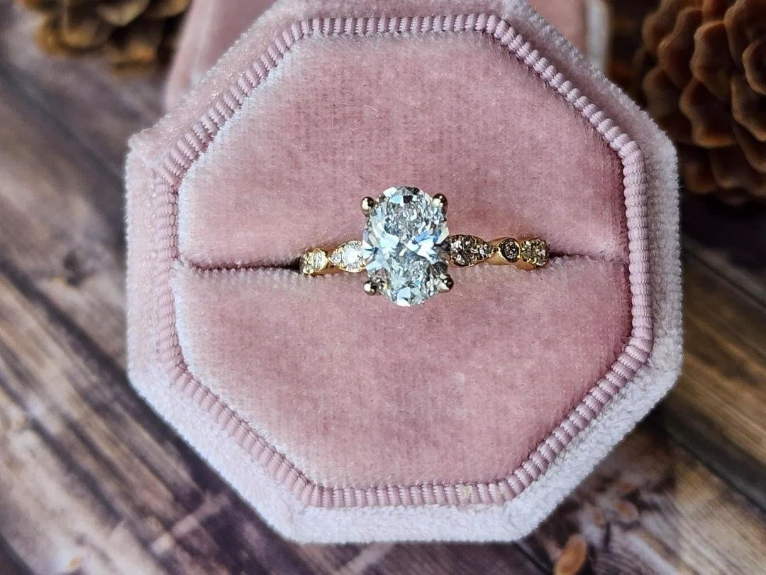 yellow gold oval lab grown diamond ring in pink box with wood back ground