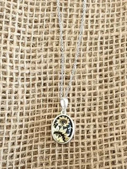 sterling silver oval amber with two carved sunflowers on a burlap background