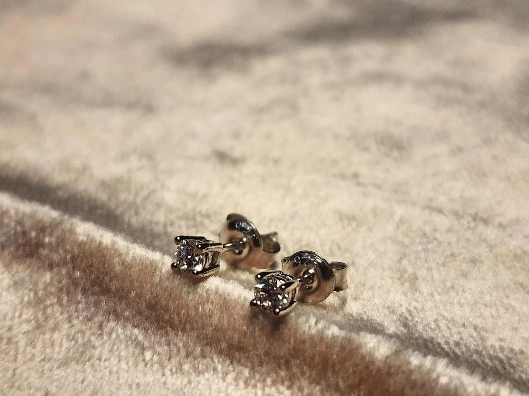 side view One pair of sterling silver Round Lab grown diamond stud earrings with post and friction backs on pink velvet background