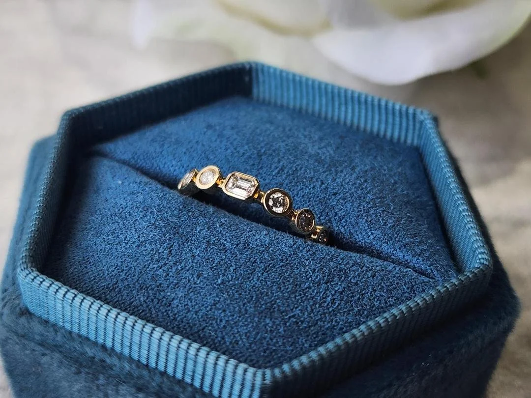 yellow gold diamond ring in a blue ring box with a white rose and grey background