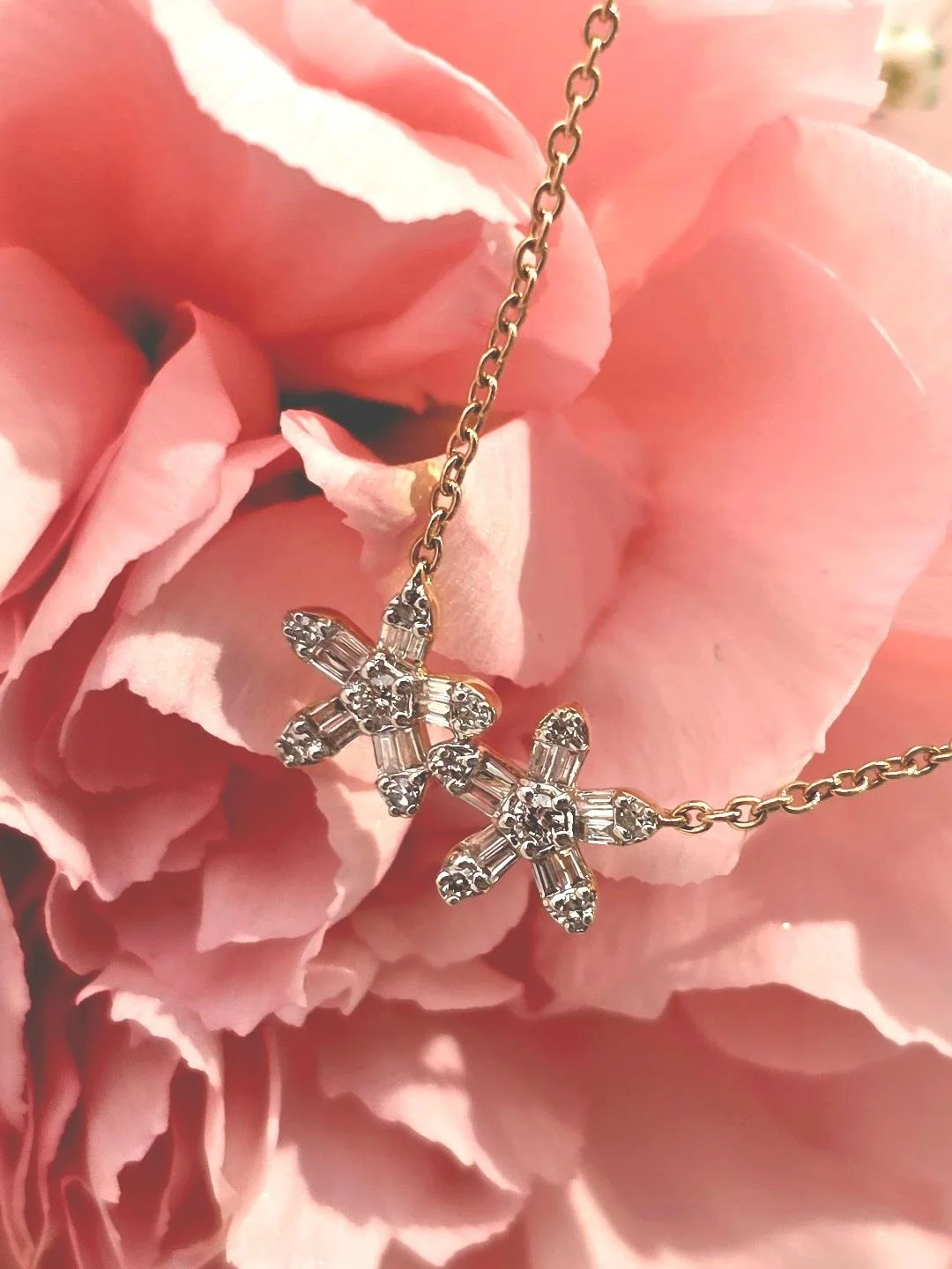 Angled view of yellow gold flower pendant set on pink carnation