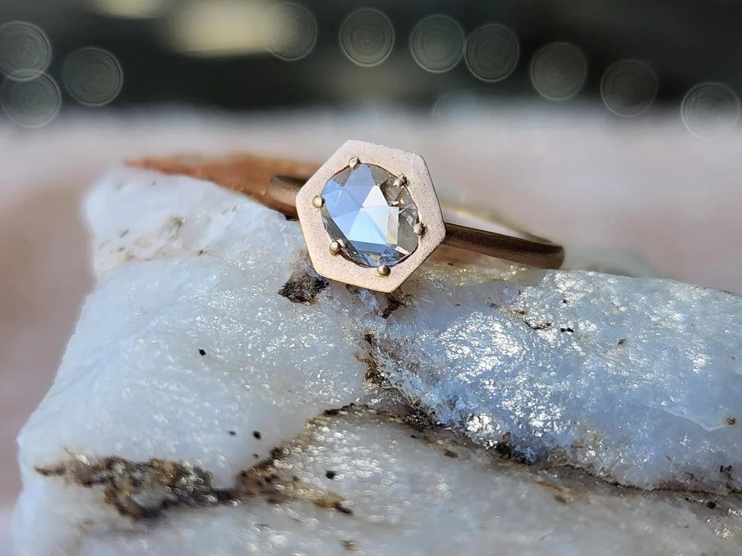 Brushed Rose gold diamond ring with rose cut diamond  resting on white quartz with pink and black background