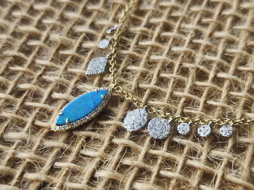Blue green boulder opal necklace with diamond accents on a burlap background