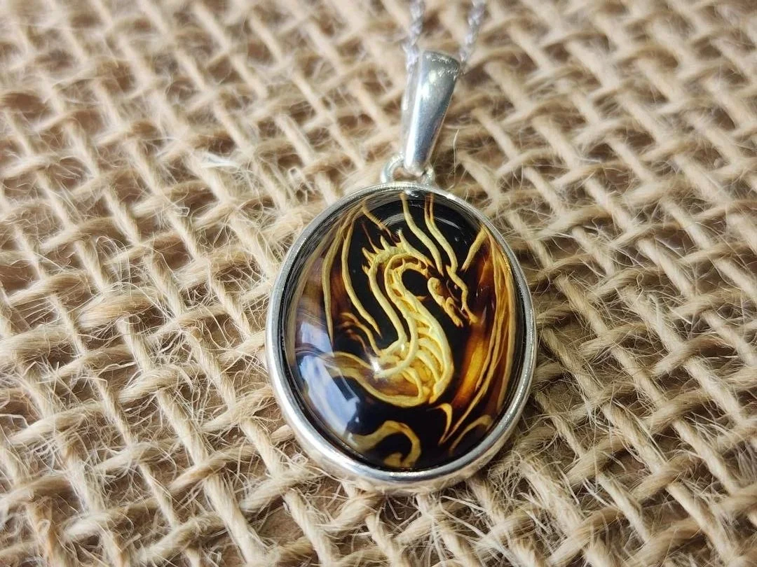 dragon carved amber necklace in sterling silver on a burlap background