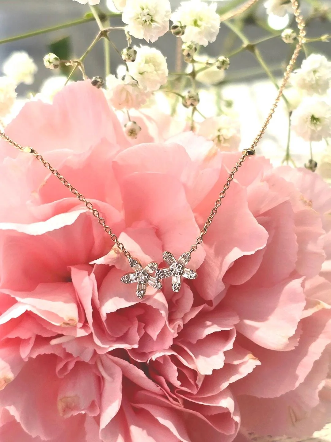 Front view of yellow gold flower pendant set on pink carnation.
