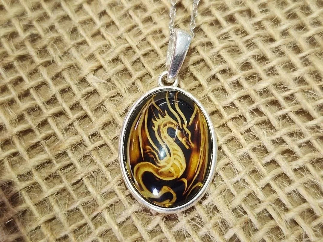 dragon carved amber necklace in sterling silver on a burlap background