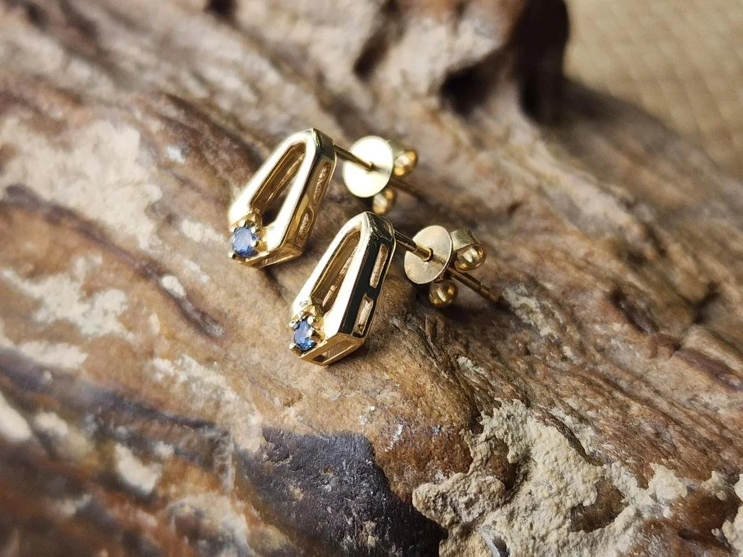 side view Yellow gold Yogo Sapphire earrings on a agatized tree