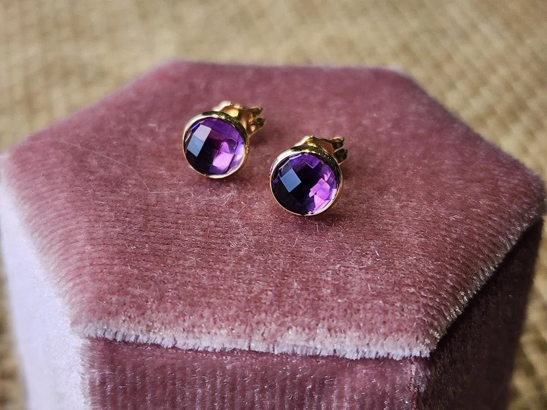 two earrings in yellow gold with a round rose cut amethyst on a pink velvet box