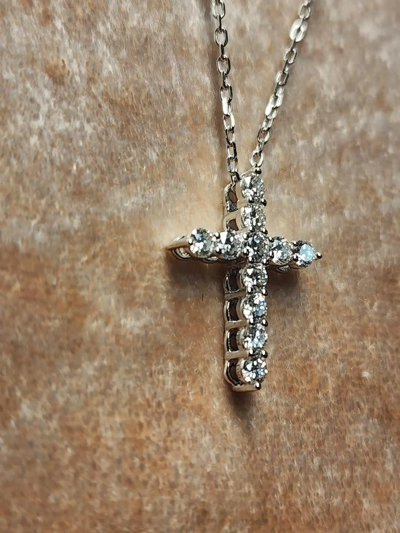 Sterling silver lab grown diamond cross necklace on chain on pink velvet background