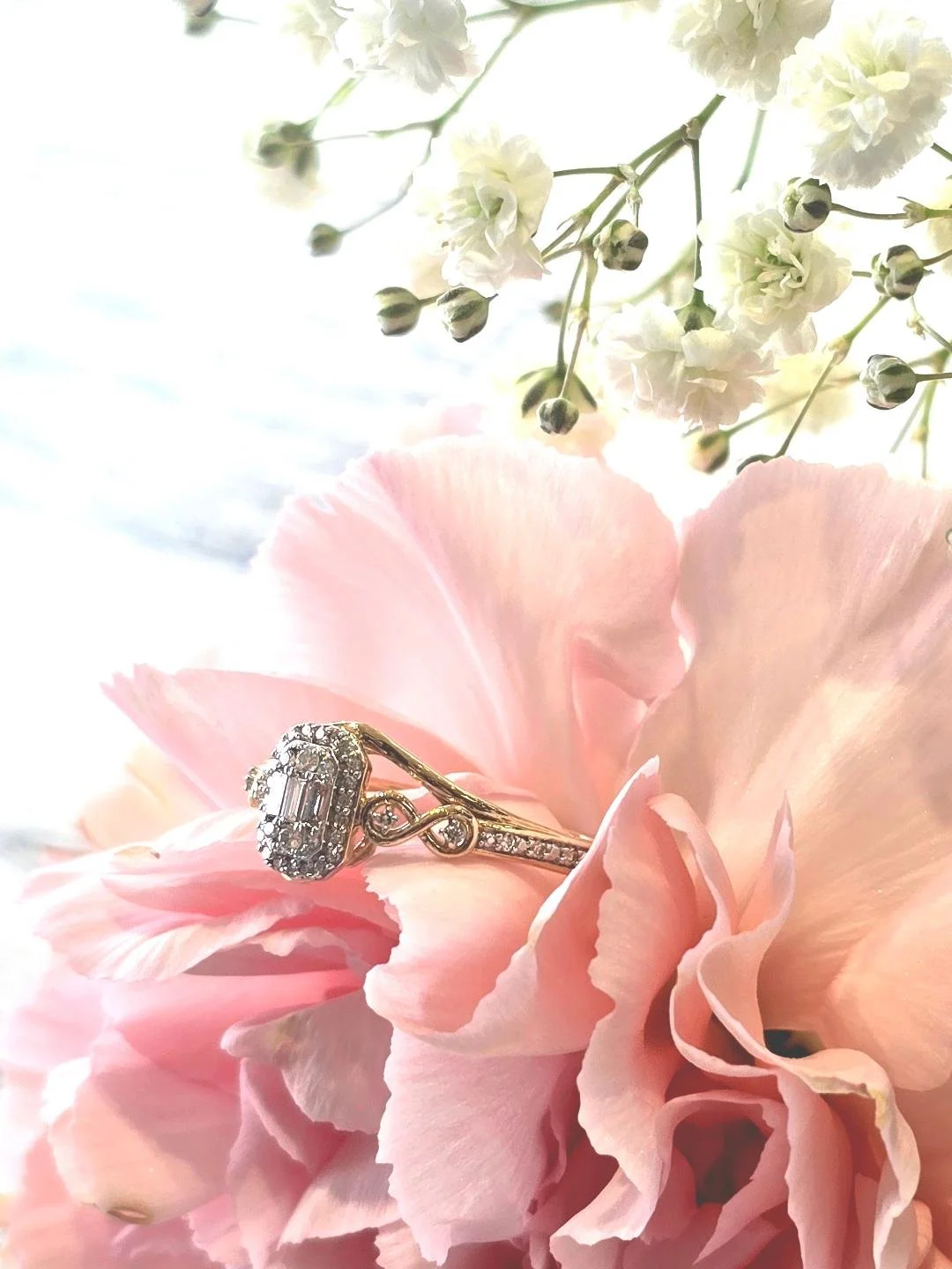 Side view of a yellow gold engagement ring set in a pink carnation with small white flowers