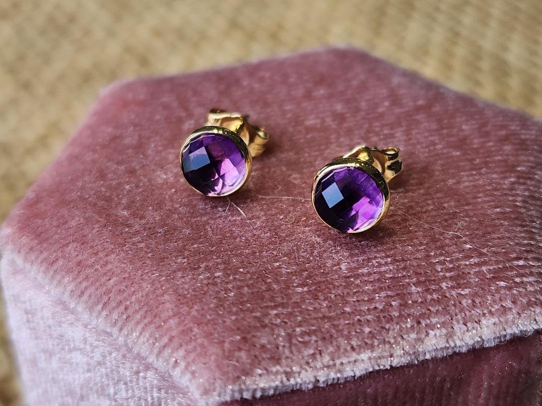 two earrings in yellow gold with a round rose cut amethyst on a pink velvet box