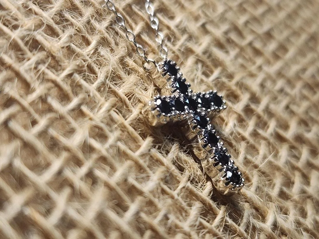 side view of Black diamond cross with silver details on a burlap background