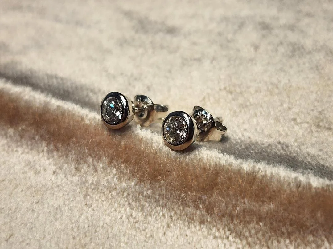 side view Bezel set round stud lab grown diamond earrings on pink velvet