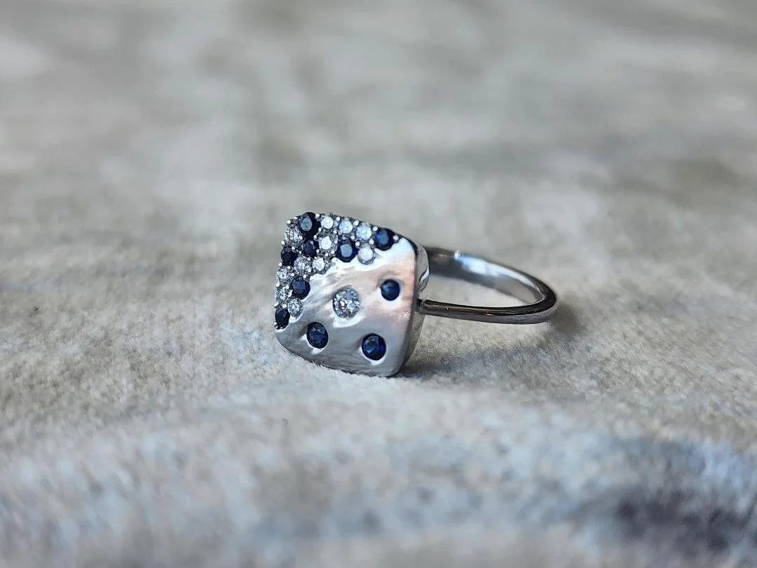white gold Sapphire and diamond ring with square top on grey fabric