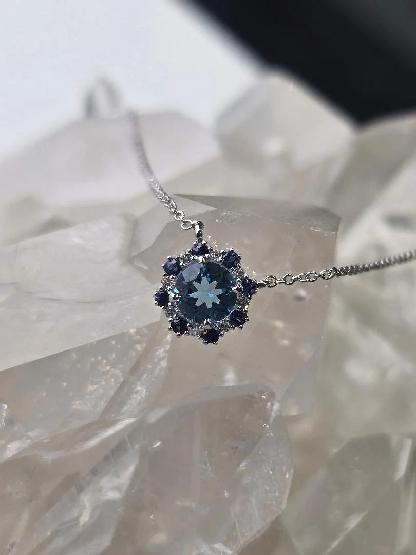 Front view of white gold blue topaz pendant with a crystal background