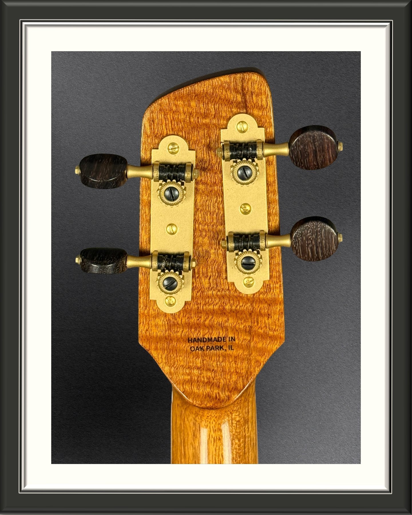 Back of the headstock of a concert ukulele with a Curly Mahogany headplate and Rubner matte brass tuners