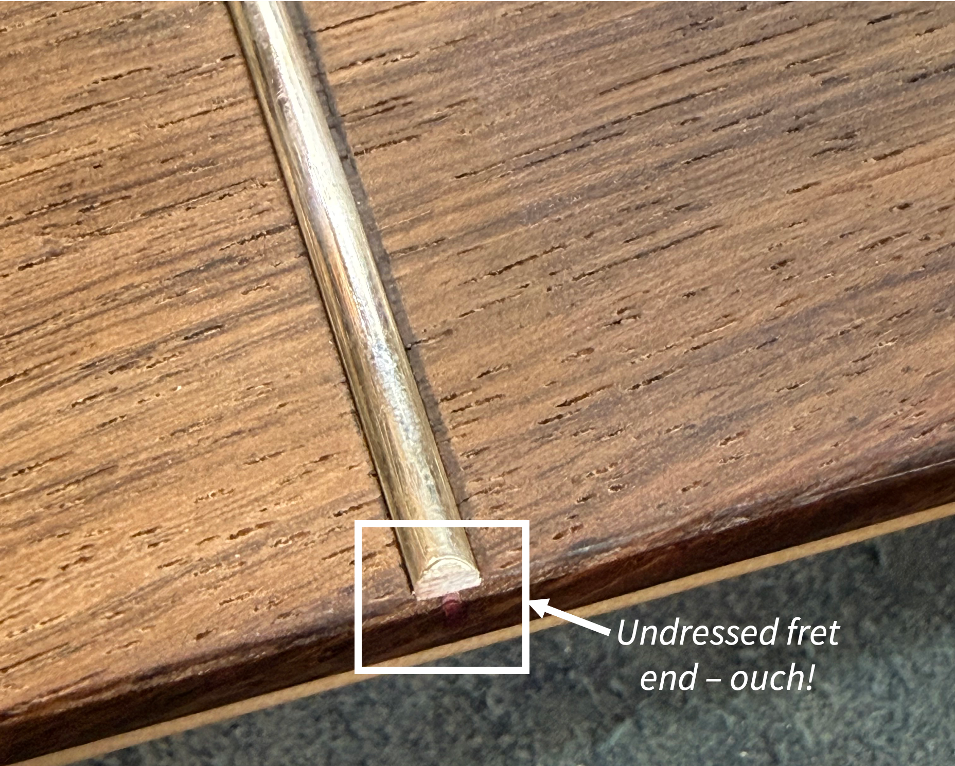 Undressed fret end at the edge of a fingerboard