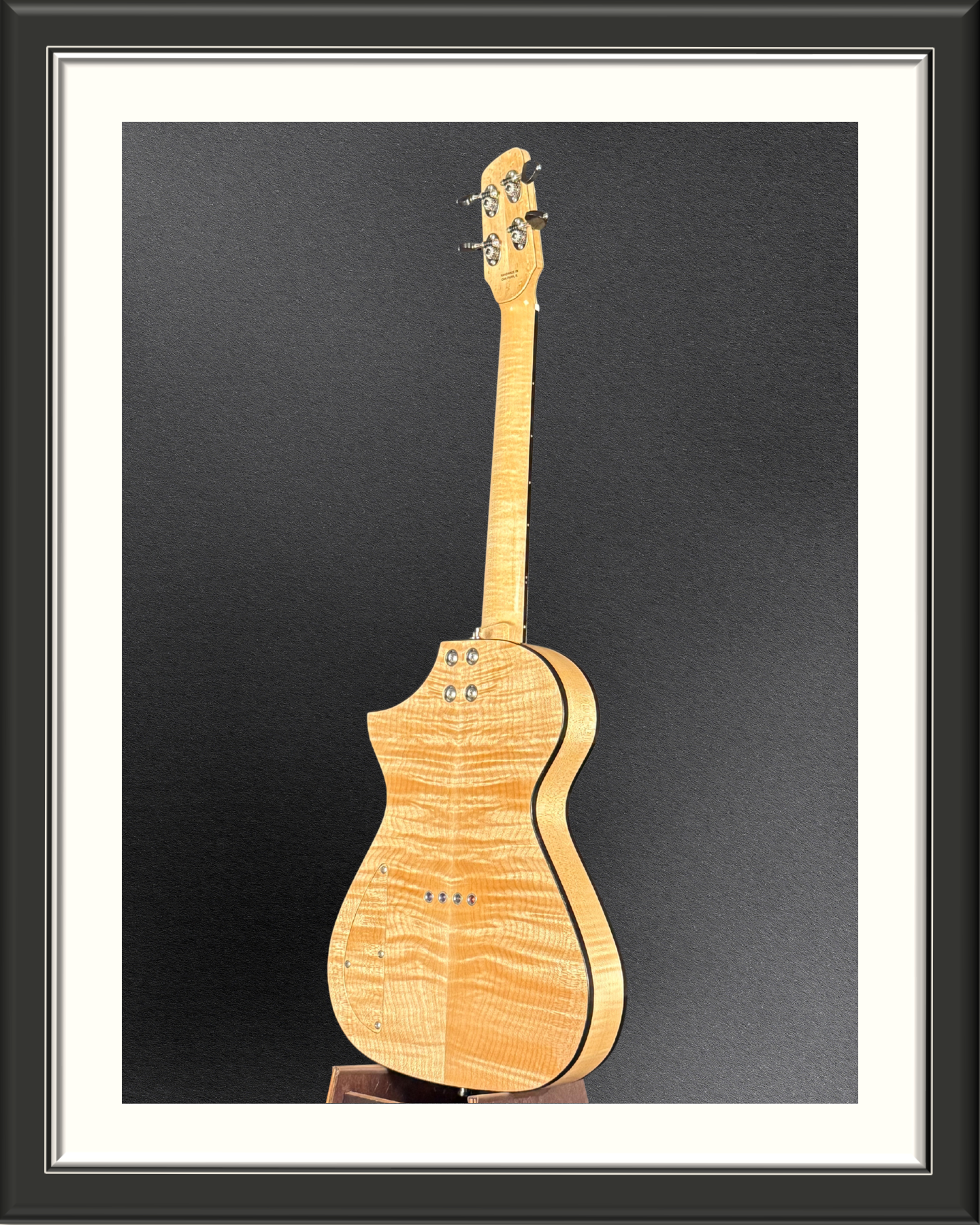Photo of the back of the MachMachines Cuyler Model all-maple, hollow-body, electric baritone ukulele at an angle with black binding