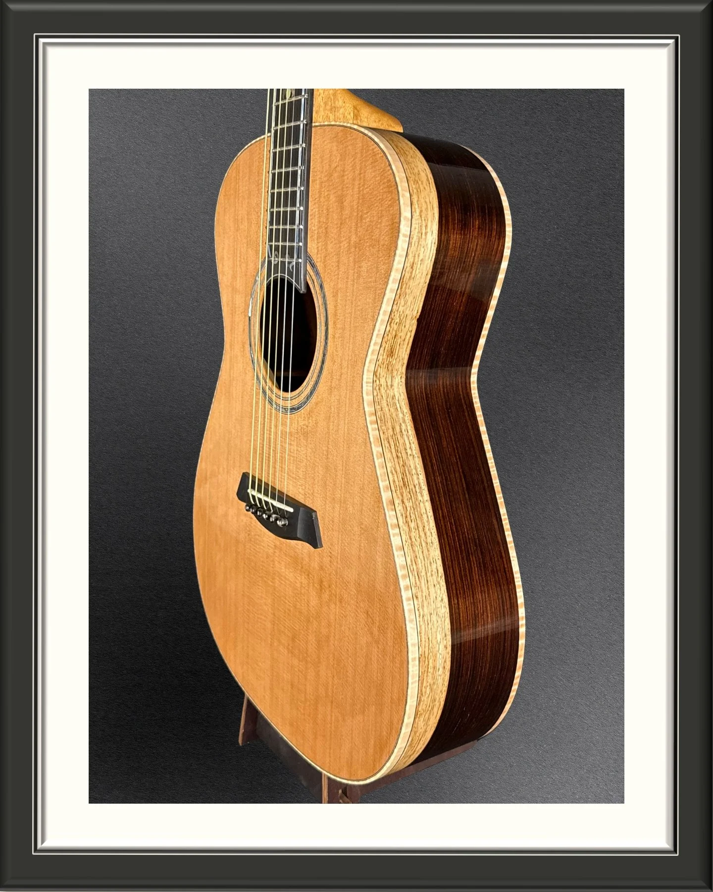 Framed photograph of an acoustic guitar body at an angle so you can see the Nicaraguan Rosewood two-tone side wood