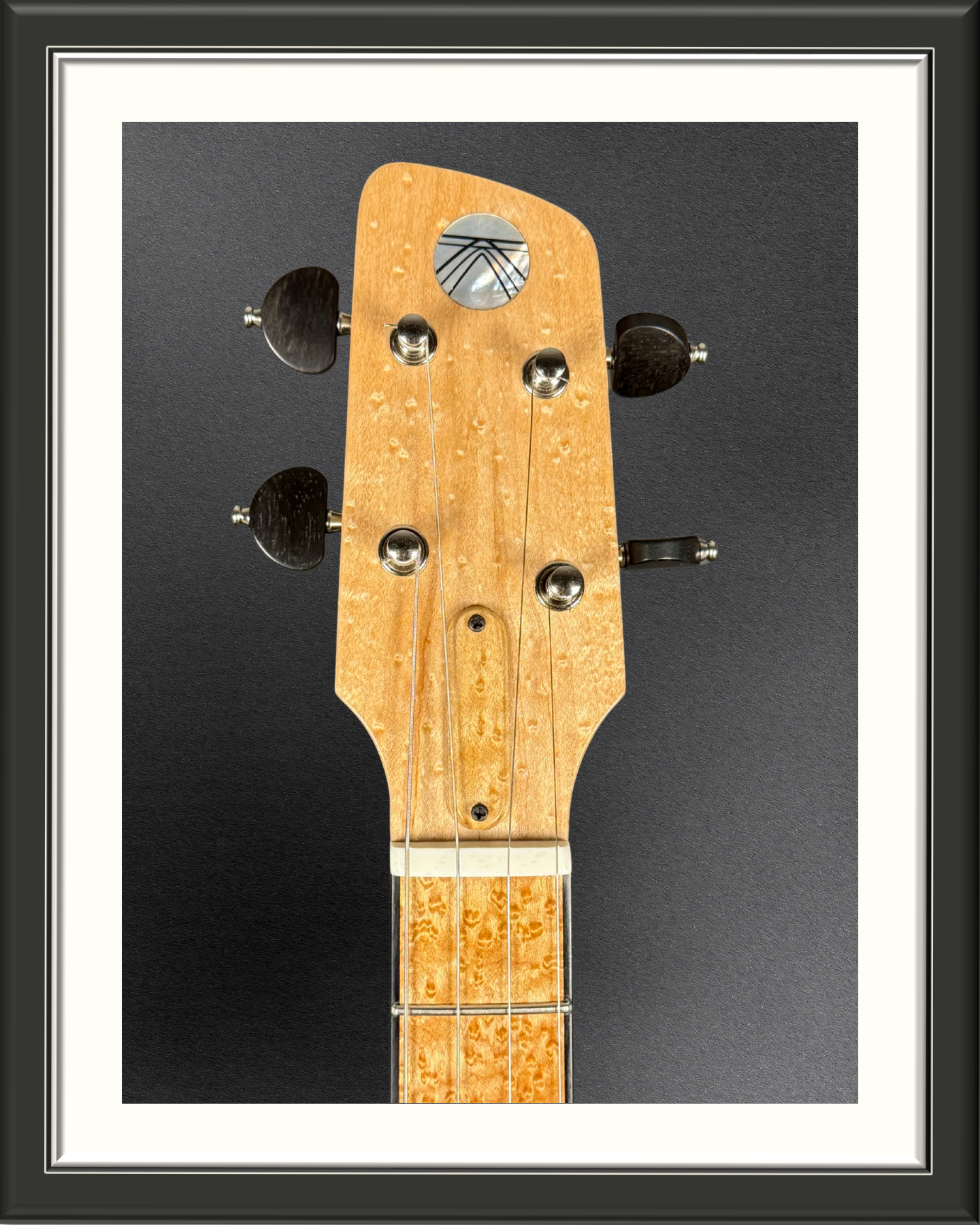 Close-up of the headstock with shockwave logo of the MachMachines Cuyler Model all-maple, hollow-body, electric baritone ukulele