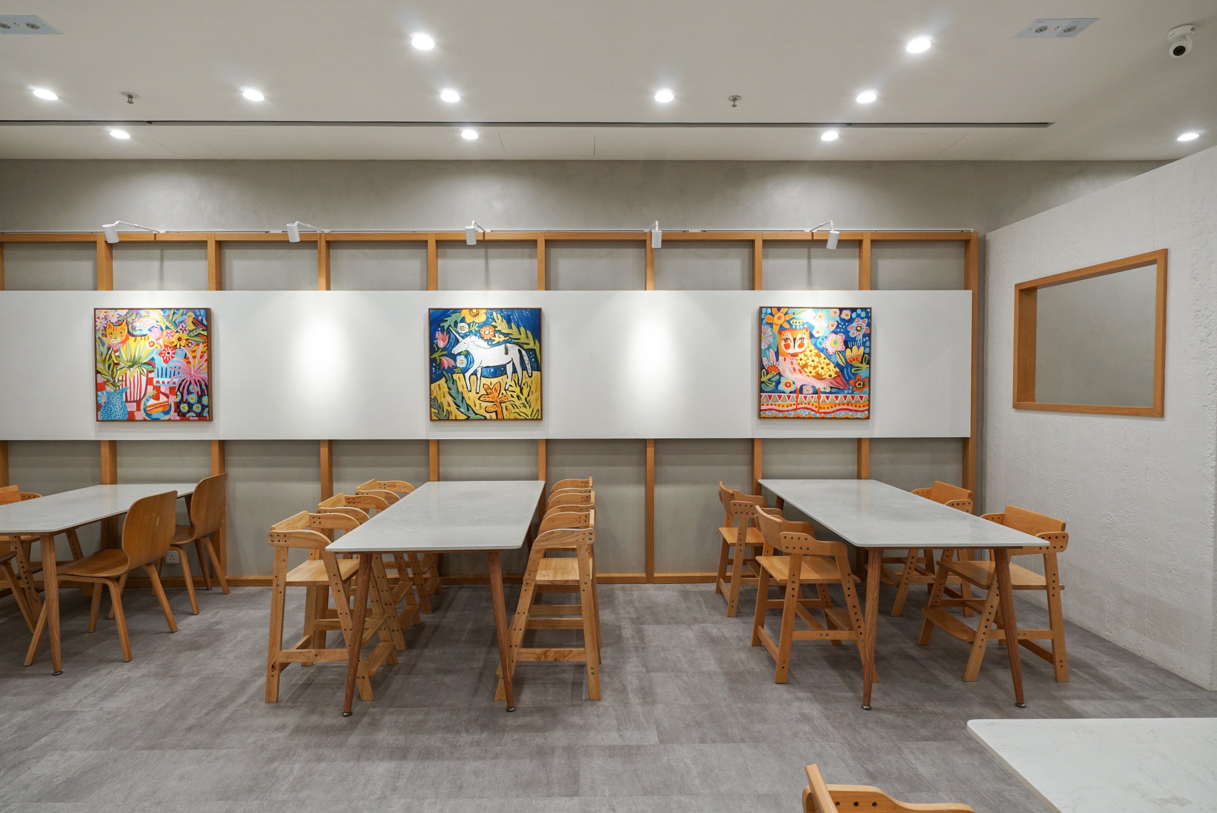 Children's art studio interior with gallery-style display walls and natural timber furniture