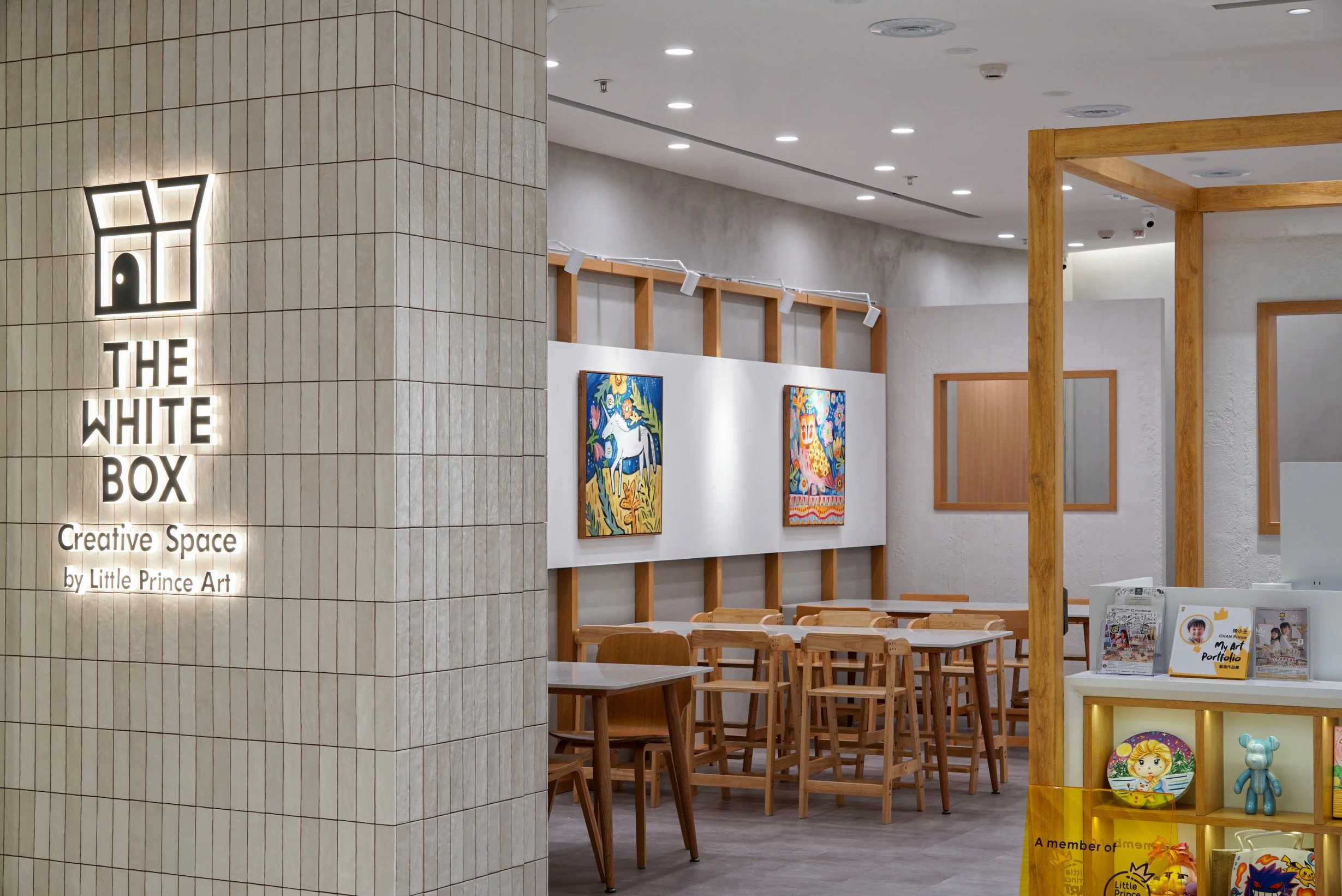 Children's art studio entrance with white handcrafted ceramic tiles and wooden framing.