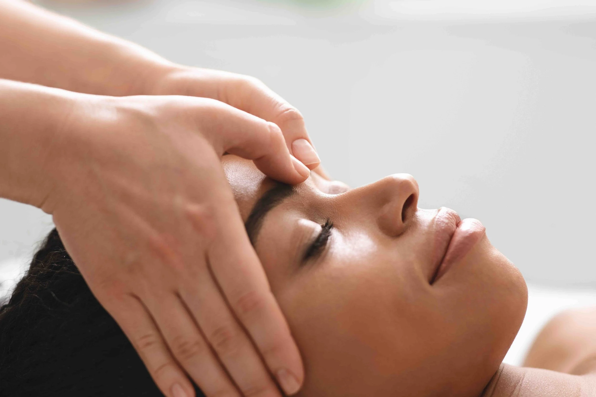 Craniosacral therapy session — practitioner applying gentle contact to a patient's head at East-West Integrated Wellness