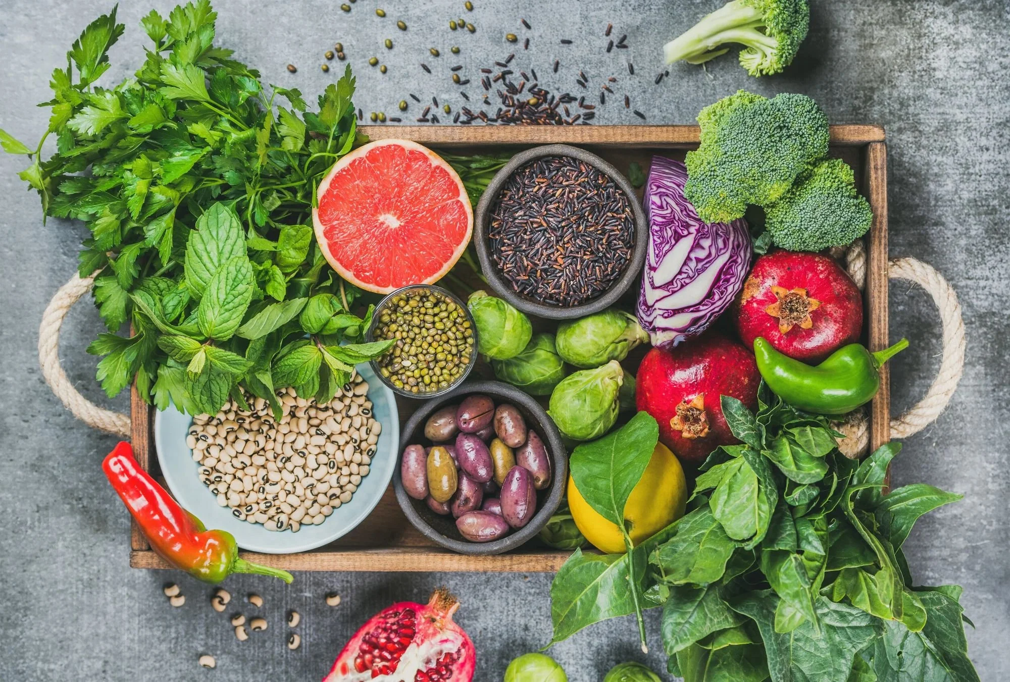 A wooden tray of vegetables, grains, and nuts used in nutritional counseling.