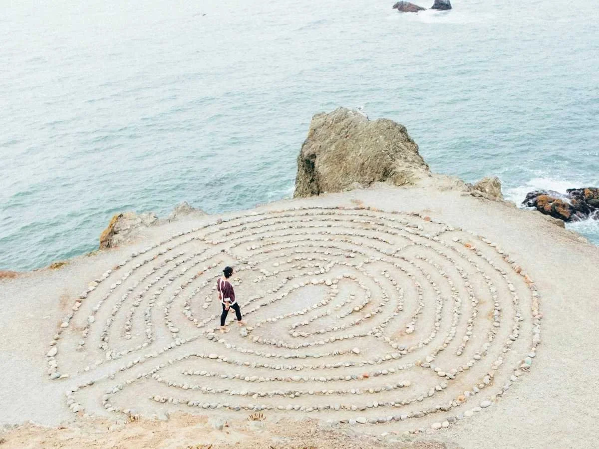 A person walking through a stone labyrinth, representing the search for the root cause of illness