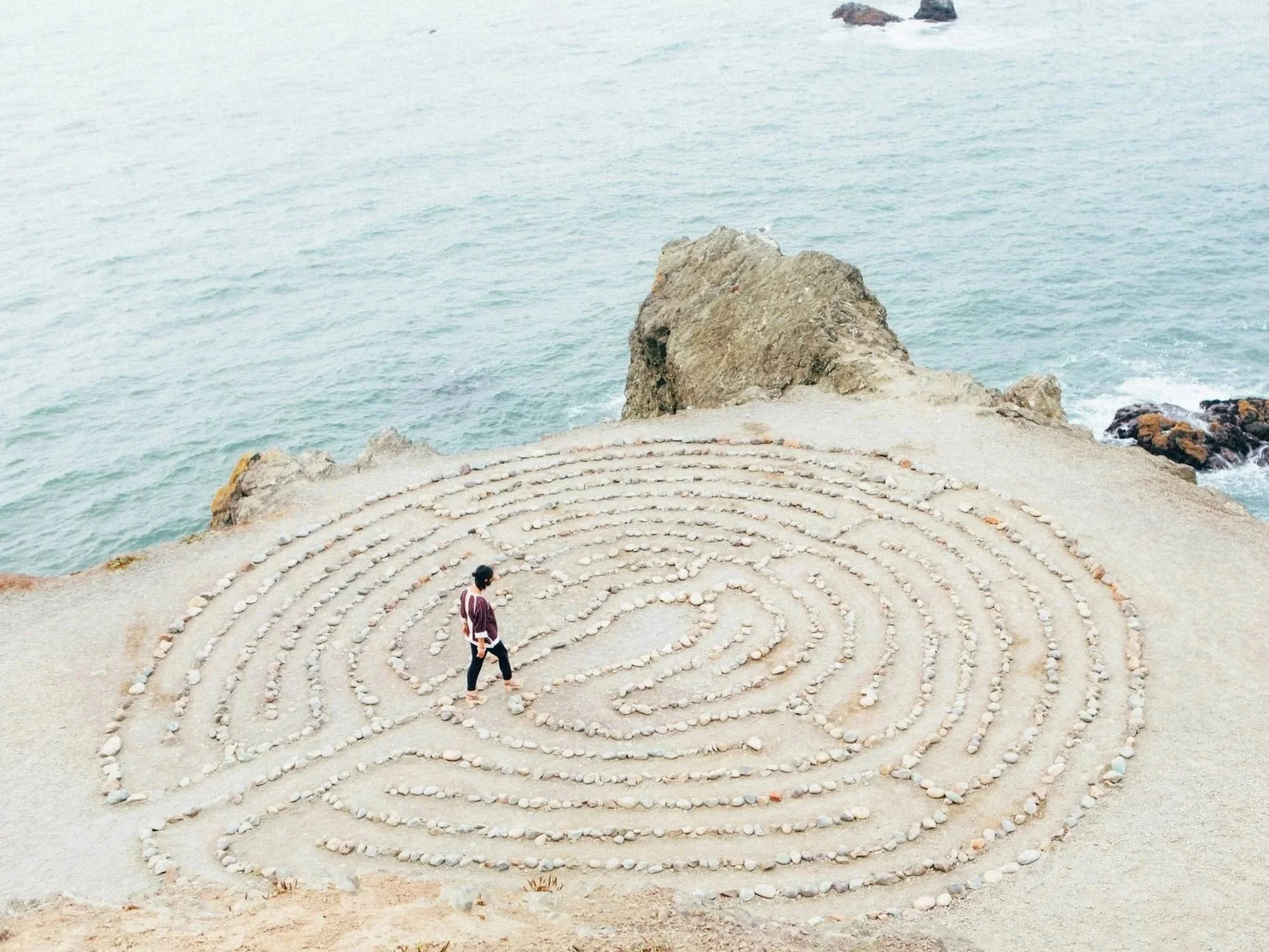 A person walking through a stone labyrinth, representing the search for the root cause of illness