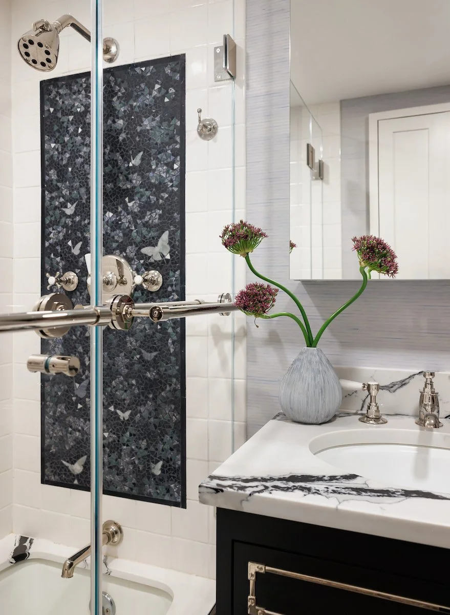 Detailed view of a Manhattan bathroom featuring glass shower enclosure, decorative stone, polished fixtures, and custom vanity.