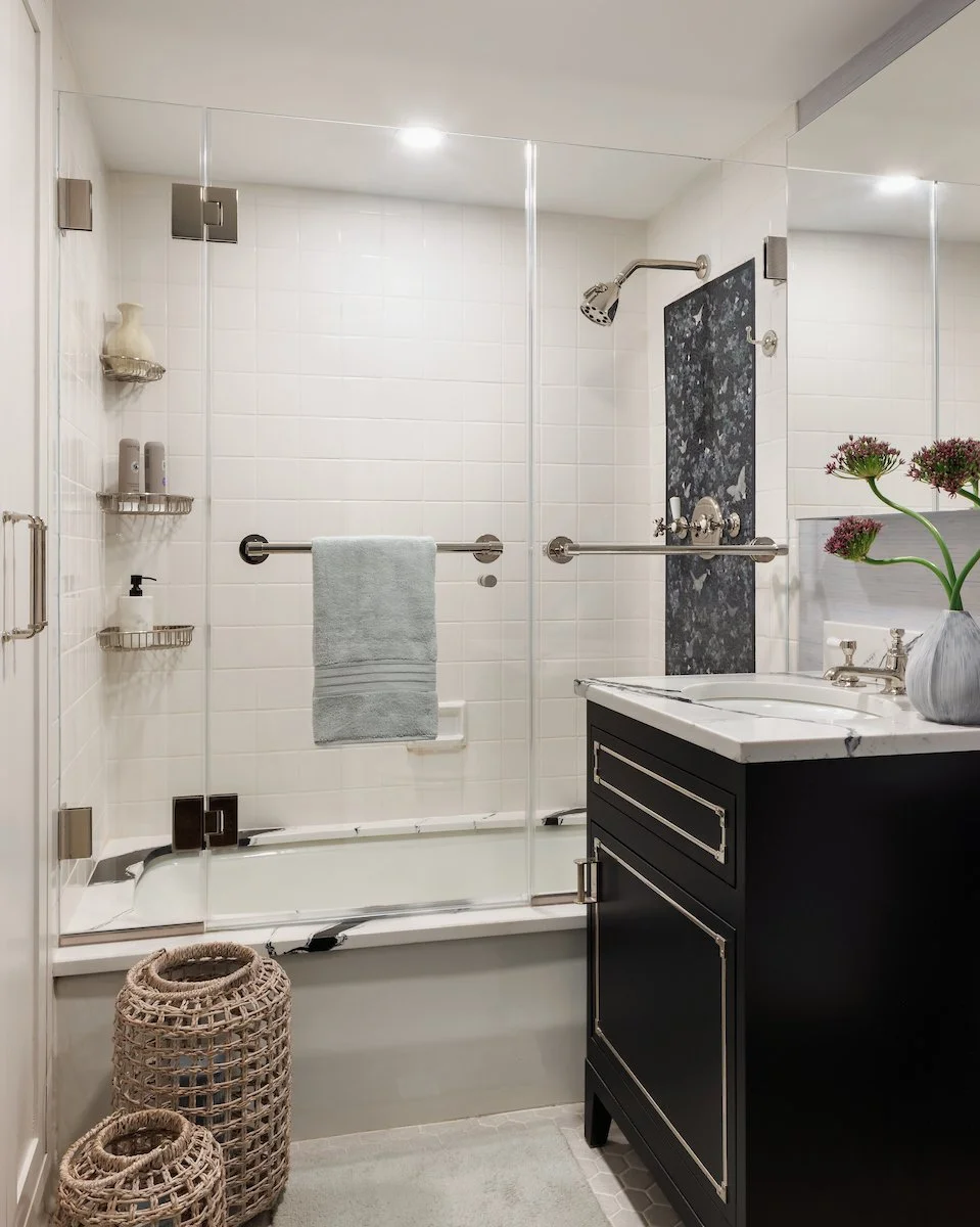 New York City bathroom design featuring a glass shower, polished fixtures, custom vanity, and timeless black-and-white finishes.