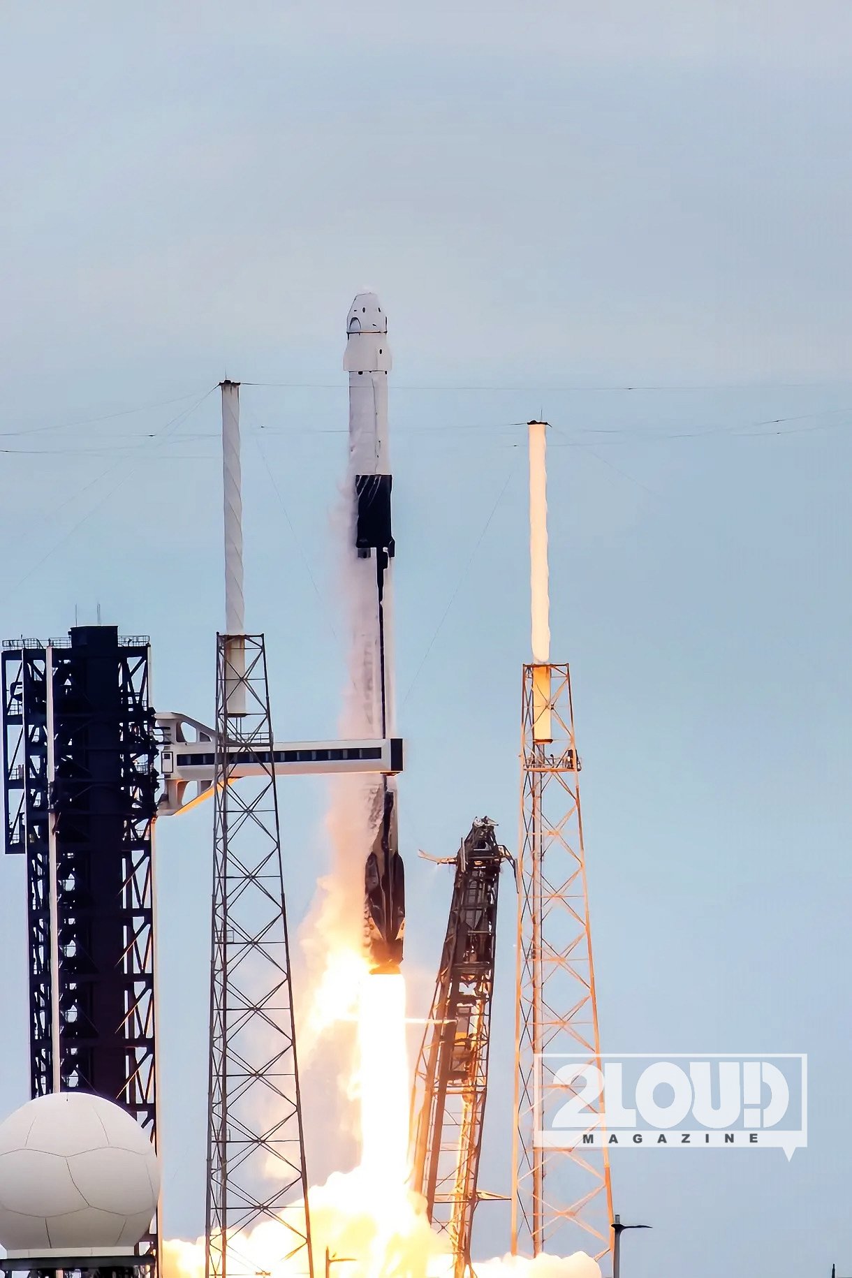 Falcon 9 carrying Crew-13 rises above the launch structures, with bright exhaust beneath the rocket.