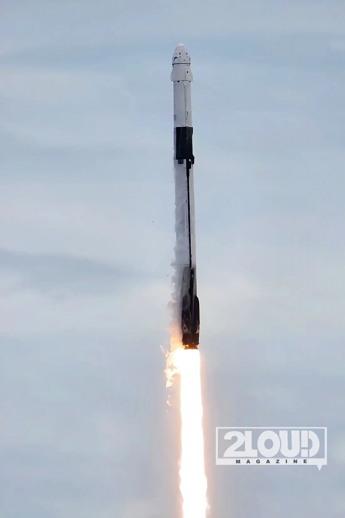Falcon 9 carrying Crew-13 rises above the launch structures, with bright exhaust beneath the rocket.