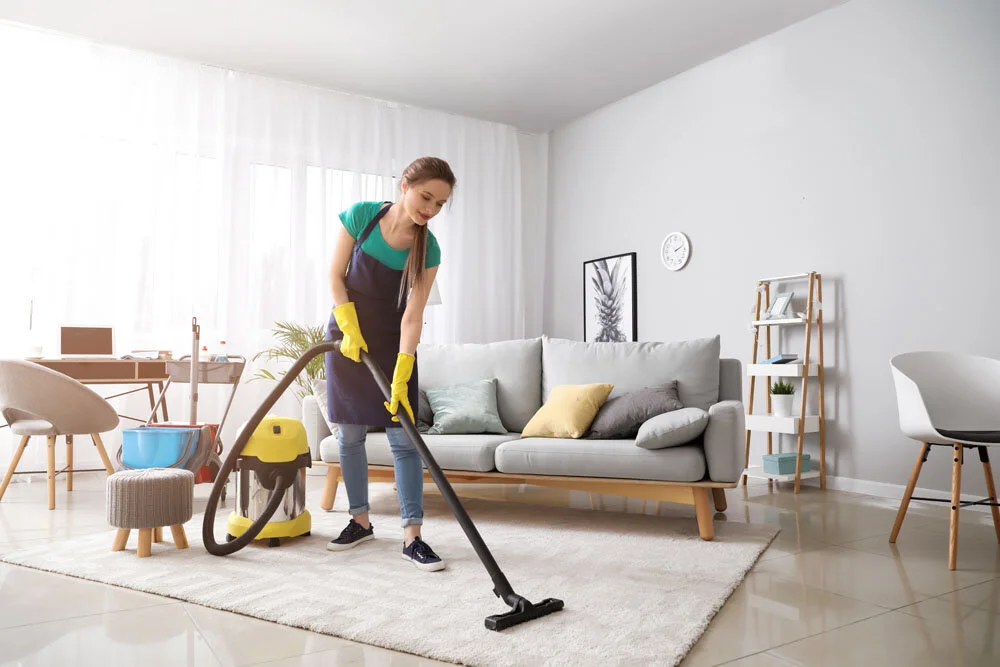 Professional home cleaner vacuuming a modern living room